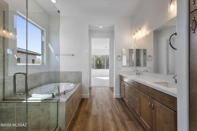 bathroom with tiled bath, hardwood / wood-style flooring, vanity, and a healthy amount of sunlight