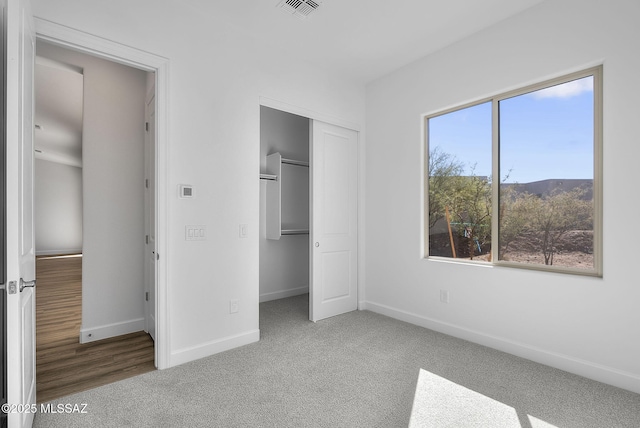 unfurnished bedroom featuring a mountain view, light colored carpet, and a closet