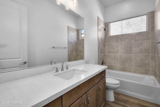full bathroom with hardwood / wood-style flooring, toilet, tiled shower / bath, and vanity