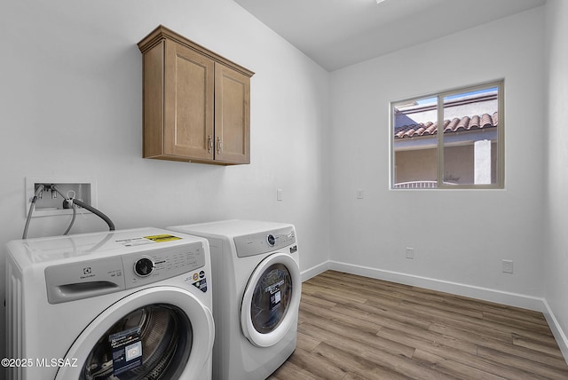 laundry room with light hardwood / wood-style flooring, cabinets, and washer and dryer