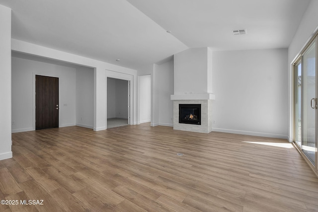unfurnished living room with plenty of natural light, light hardwood / wood-style flooring, and vaulted ceiling