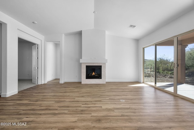 unfurnished living room with a tiled fireplace and light wood-type flooring