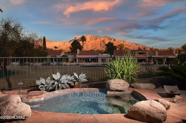 pool at dusk featuring a mountain view