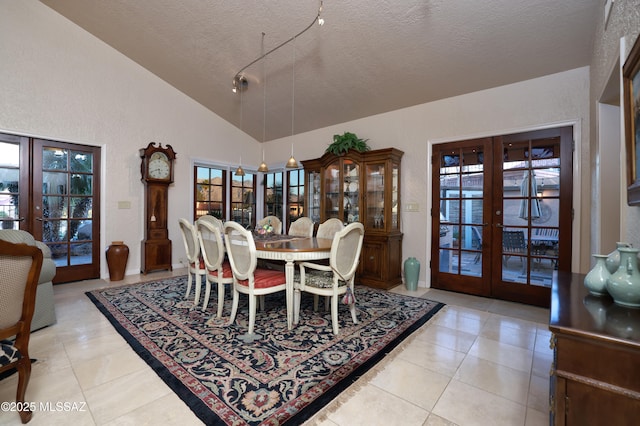 dining area with high vaulted ceiling, french doors, light tile patterned flooring, and a textured ceiling