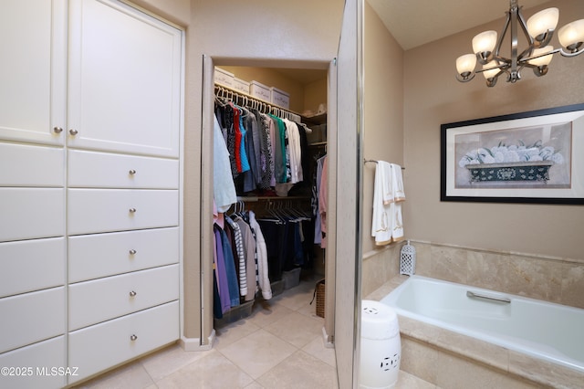 bathroom with tiled bath, a notable chandelier, and tile patterned flooring