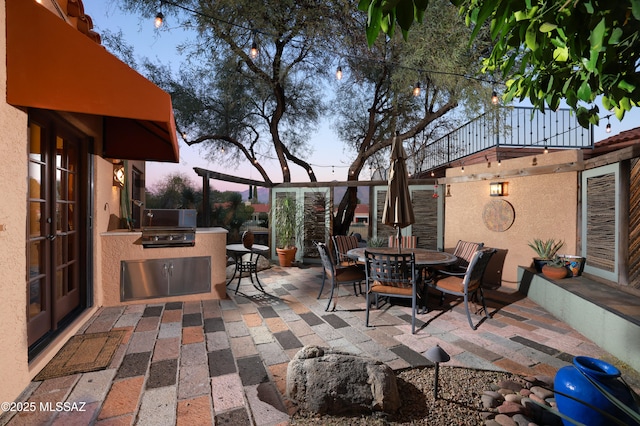 patio terrace at dusk featuring area for grilling