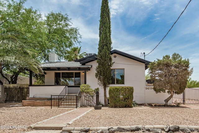 view of front of property with fence, a chimney, and stucco siding