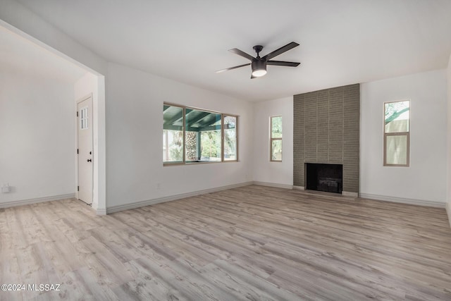 unfurnished living room featuring ceiling fan, light wood-type flooring, and a brick fireplace