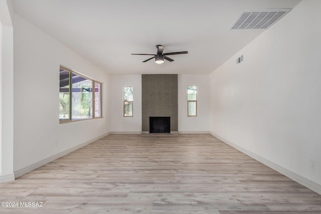 unfurnished living room with ceiling fan, a large fireplace, and light hardwood / wood-style floors