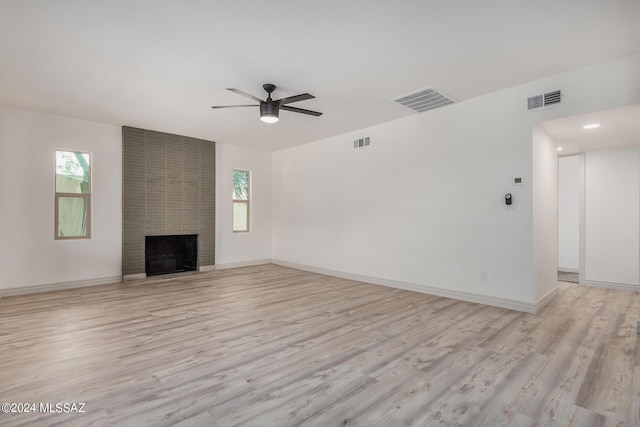 unfurnished living room with a fireplace, a healthy amount of sunlight, ceiling fan, and light wood-type flooring