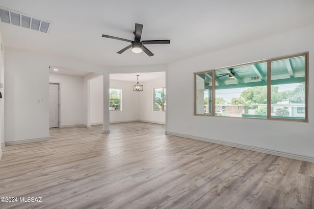 empty room featuring ceiling fan with notable chandelier and light wood-type flooring