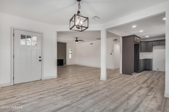 interior space with a healthy amount of sunlight, ceiling fan with notable chandelier, and light hardwood / wood-style floors