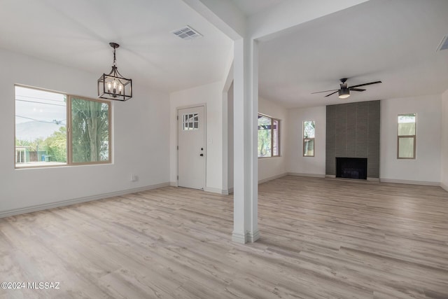 unfurnished living room with light wood-type flooring, a fireplace, and ceiling fan with notable chandelier