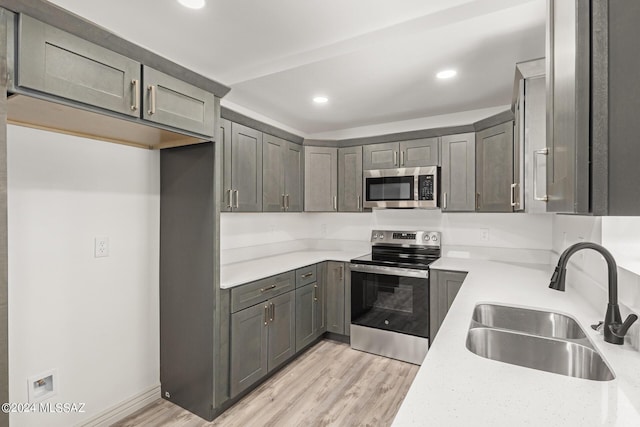 kitchen featuring sink, light stone counters, stainless steel appliances, and light hardwood / wood-style flooring