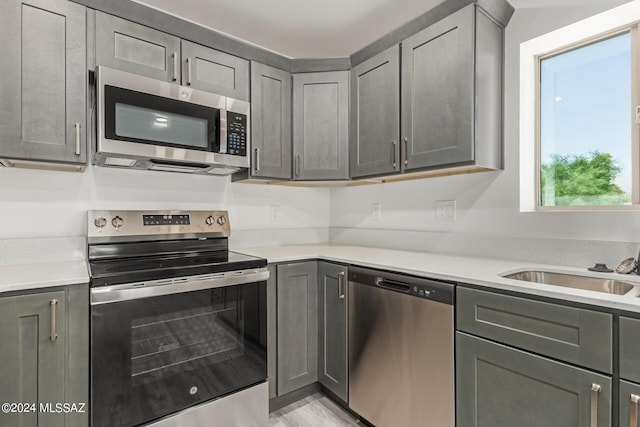 kitchen with appliances with stainless steel finishes, gray cabinetry, and sink