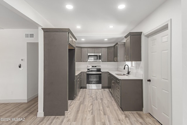 kitchen with sink, appliances with stainless steel finishes, and light hardwood / wood-style flooring