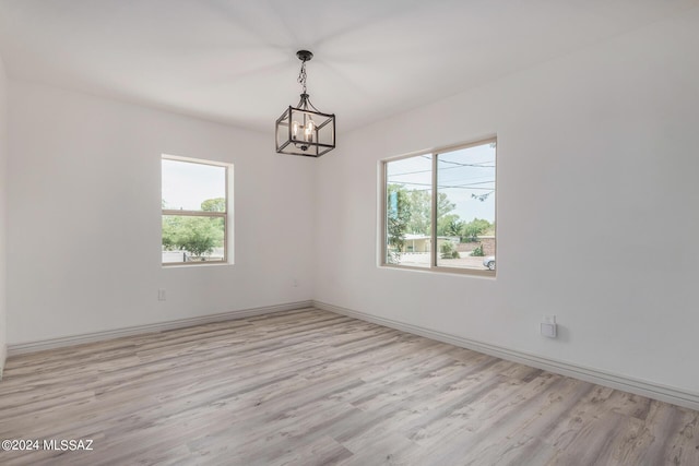 empty room with a notable chandelier and light hardwood / wood-style flooring