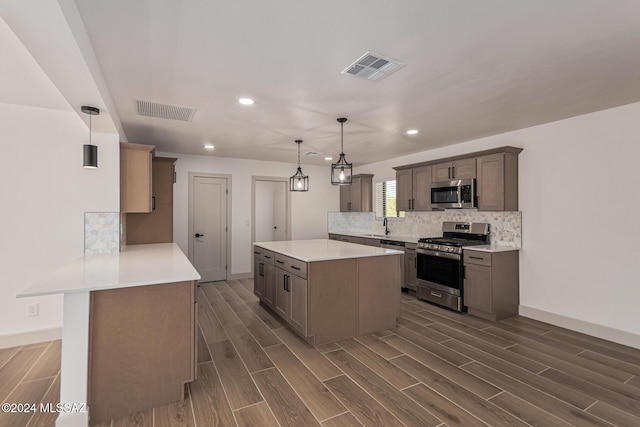 kitchen featuring dark hardwood / wood-style floors, pendant lighting, decorative backsplash, sink, and stainless steel appliances