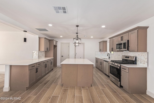 kitchen with stainless steel appliances, tasteful backsplash, hanging light fixtures, and sink