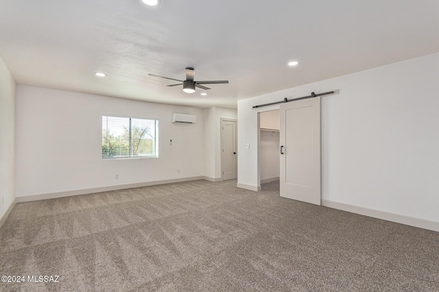 unfurnished bedroom with ceiling fan, carpet, a wall mounted AC, and a barn door