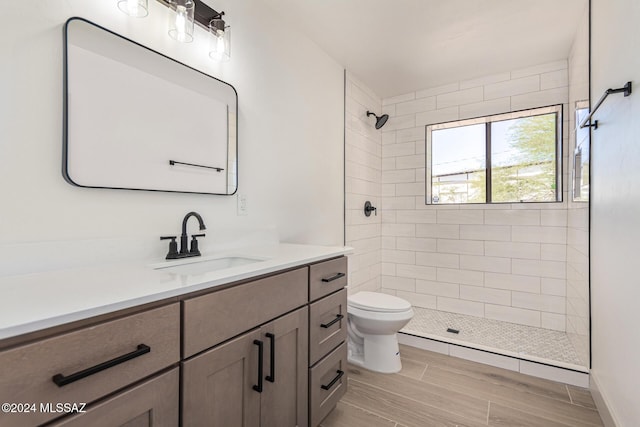 bathroom featuring toilet, vanity, and tiled shower