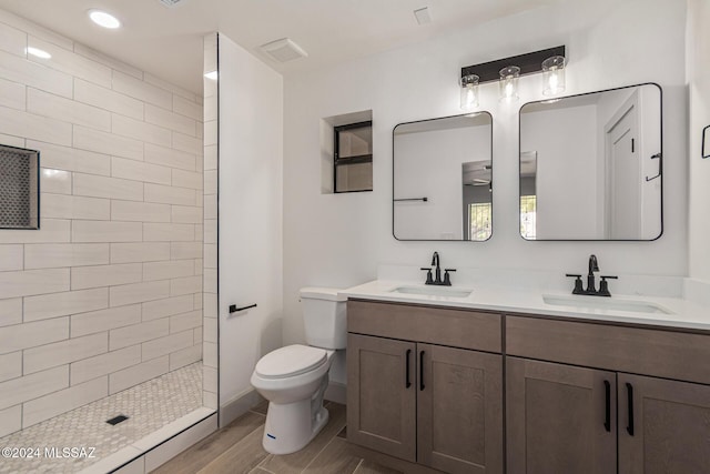 bathroom with toilet, vanity, and tiled shower