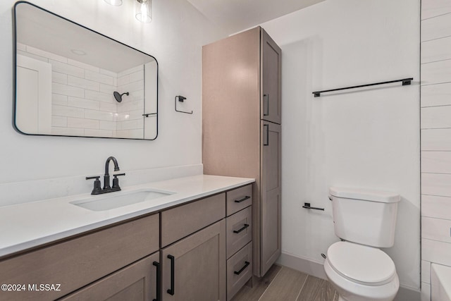 bathroom featuring toilet, walk in shower, and vanity