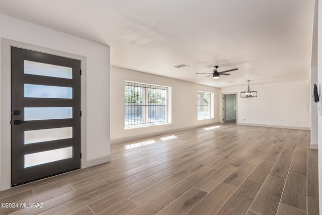 entryway with ceiling fan with notable chandelier and hardwood / wood-style flooring