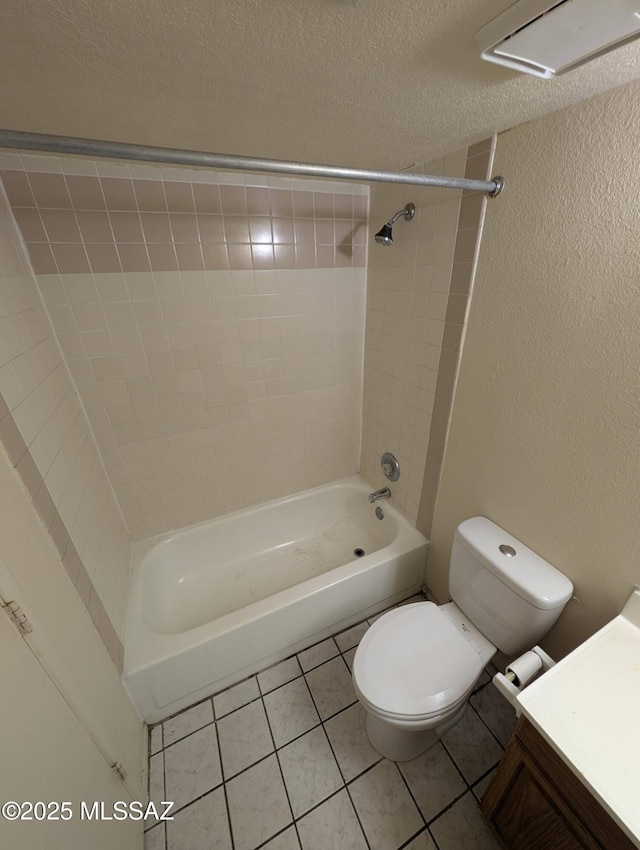 full bathroom featuring tile patterned floors, toilet, tiled shower / bath, a textured ceiling, and vanity