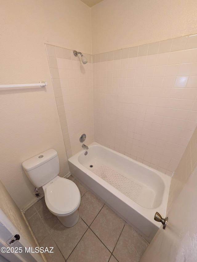 bathroom featuring tile patterned flooring, tiled shower / bath combo, and toilet