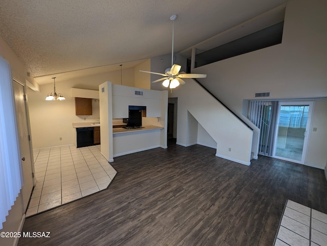 unfurnished living room with hardwood / wood-style floors, ceiling fan with notable chandelier, high vaulted ceiling, and a textured ceiling