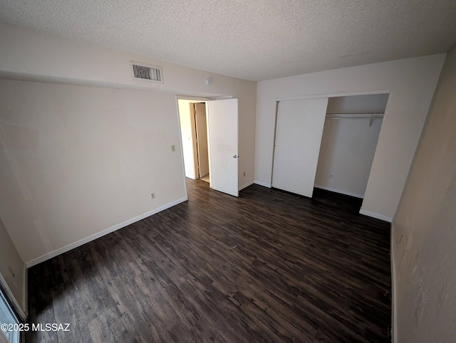 unfurnished bedroom featuring a textured ceiling, dark hardwood / wood-style flooring, and a closet