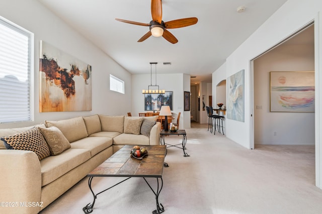 living room with light carpet and ceiling fan with notable chandelier