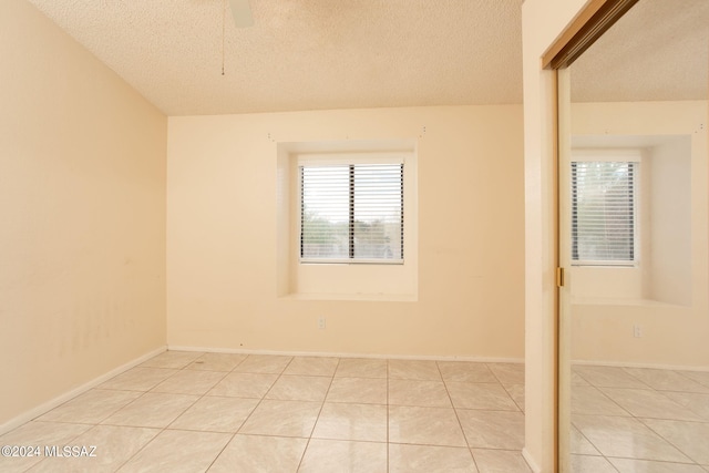 unfurnished room featuring a textured ceiling, ceiling fan, and light tile patterned floors