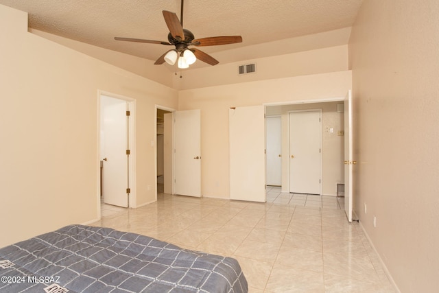 unfurnished bedroom with ceiling fan, vaulted ceiling, and a textured ceiling