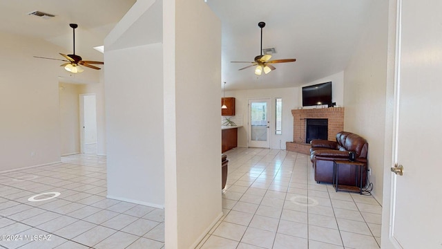 tiled living room with a fireplace, ceiling fan, and vaulted ceiling