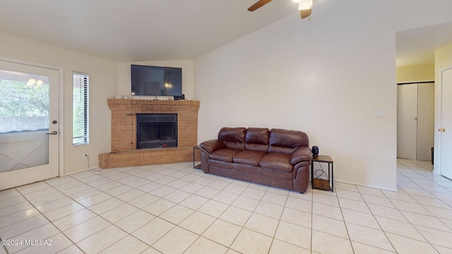 tiled living room featuring ceiling fan, a brick fireplace, and vaulted ceiling