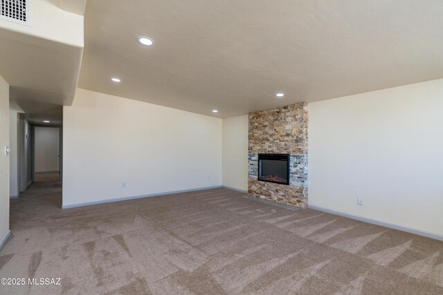 unfurnished living room featuring light carpet, a healthy amount of sunlight, and a stone fireplace