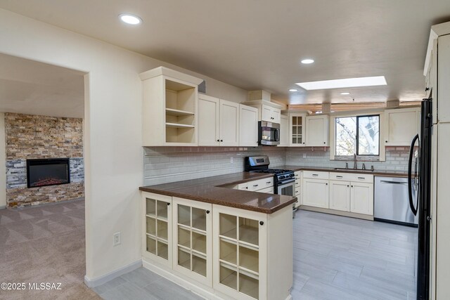 kitchen with recessed lighting, glass insert cabinets, black fridge with ice dispenser, and decorative backsplash