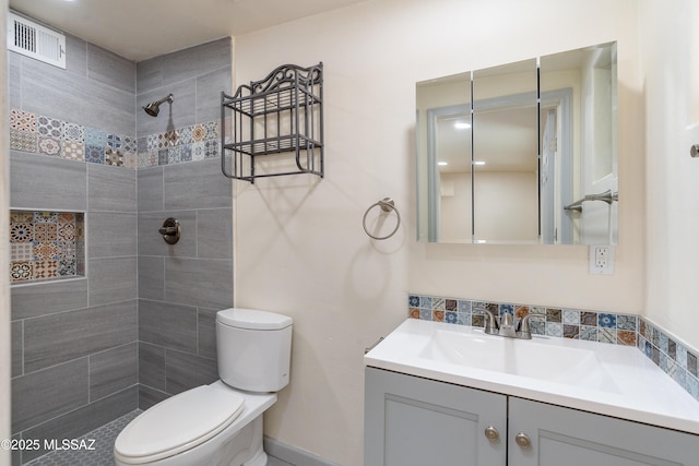 bathroom featuring vanity, tiled shower, and toilet