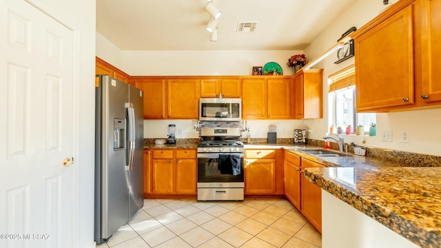 kitchen featuring sink, appliances with stainless steel finishes, dark stone counters, and light tile patterned flooring