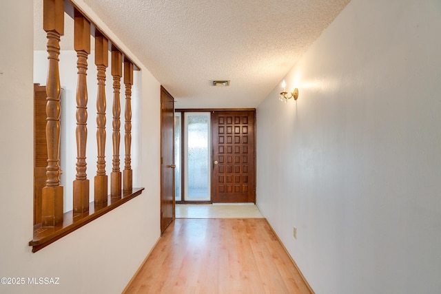 doorway to outside featuring light hardwood / wood-style flooring and a textured ceiling