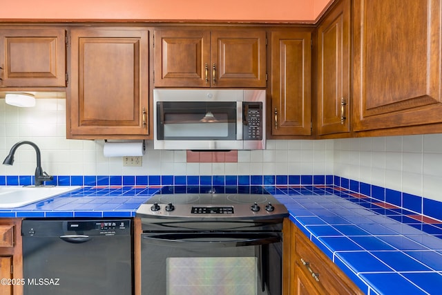 kitchen with dishwasher, range with electric cooktop, tile countertops, and backsplash