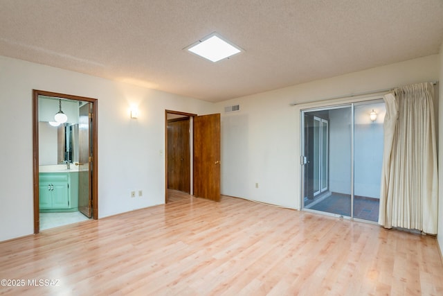 unfurnished room with sink, light wood-type flooring, and a textured ceiling