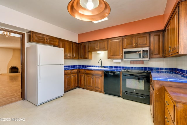 kitchen featuring sink, white refrigerator, tile countertops, electric range, and black dishwasher