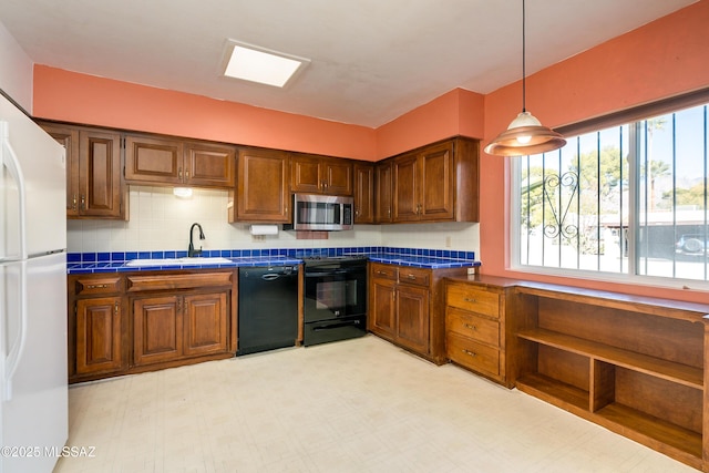 kitchen with sink, backsplash, black appliances, and pendant lighting