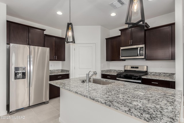 kitchen featuring light tile patterned floors, stainless steel appliances, light stone counters, dark brown cabinetry, and sink