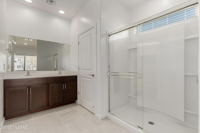 bathroom with a shower with shower door, tile patterned floors, and vanity