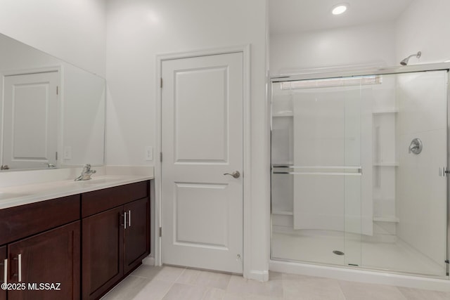 bathroom featuring a shower with shower door, vanity, and tile patterned flooring