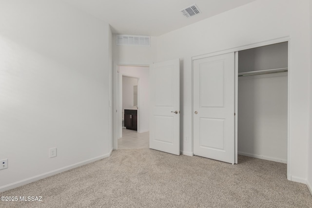 unfurnished bedroom featuring light carpet and a closet